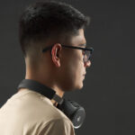 Hombre con gafas con audifonos y camseta Beige